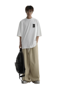 Model wearing Masonprince WashTag Tee white oversized t-shirt paired with beige wide-leg pants and carrying black backpack