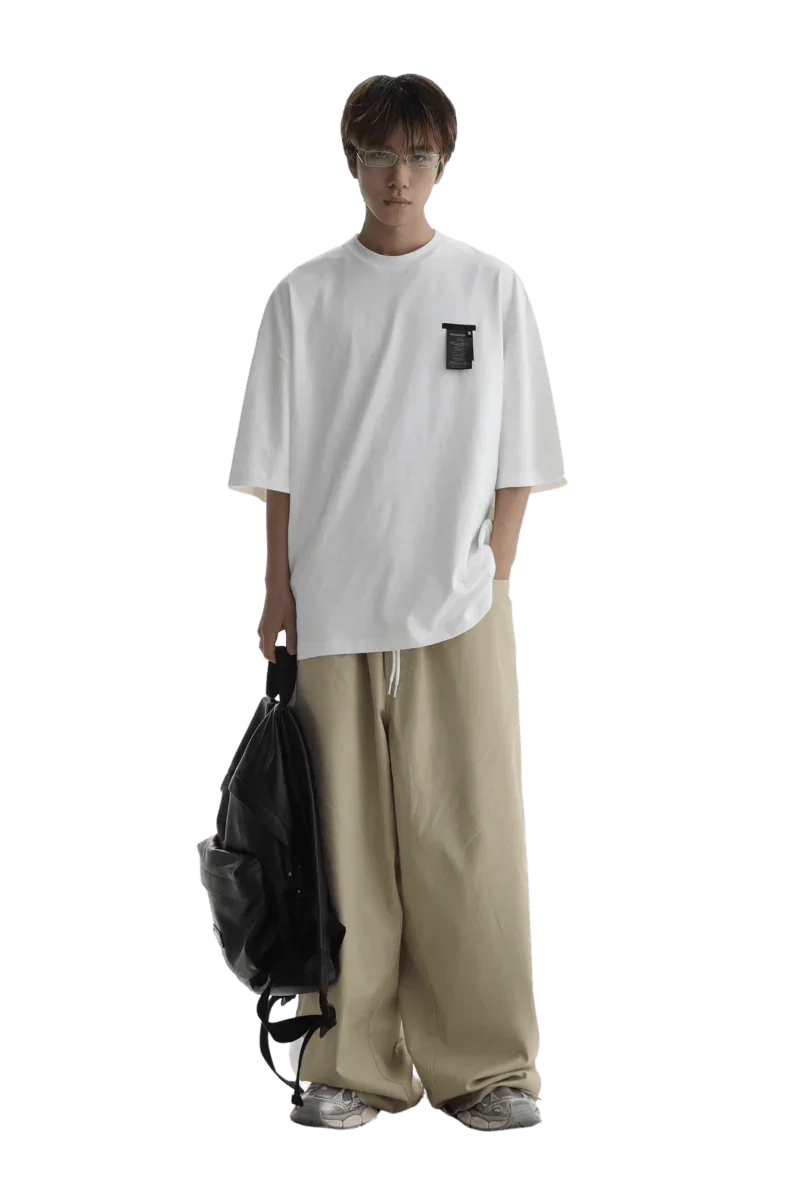 Model wearing Masonprince WashTag Tee white oversized t-shirt paired with beige wide-leg pants and carrying black backpack