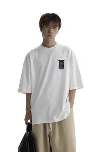 Model wearing a white Masonprince WashTag Tee with a black tag detail on the chest and beige pants