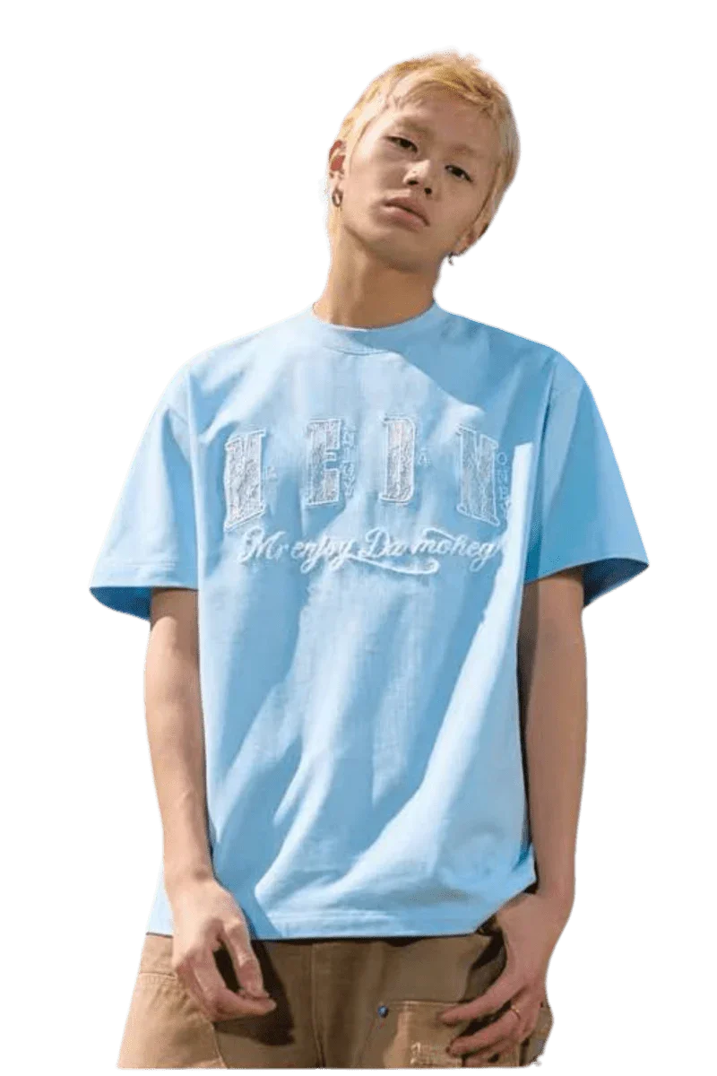 Young man wearing a light blue MEDM Burnt Laced Tee by Mr Enjoy Da Money with distressed lettering