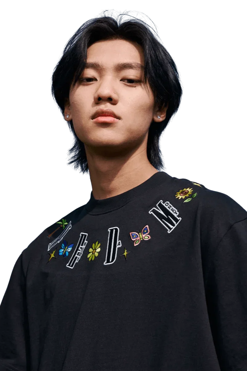 Young man wearing black MEDM Butterfly Necklace Embroidery Tee with colorful butterfly and floral designs around the neckline