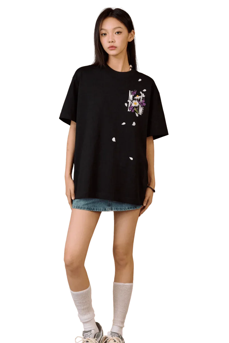 Woman wearing black MEDM Falling Petals Embroidery Tee with floral design paired with denim shorts