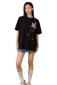 Woman wearing black MEDM Falling Petals Embroidery Tee with floral design paired with denim shorts