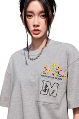 MEDM Flower Embroidery Pocket Tee in gray featuring vibrant floral design and relaxed fit