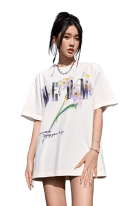 Woman wearing a white MEDM Smudged Floral Tee with purple flowers and graphic text design