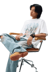 Model wearing a MEDM SS24 Phoenix Series Print Tee with ripped jeans, seated in a modern chair.