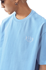Light blue MEDM SS25 Basic Embroidery Tee designed for a relaxed fit with stylish logo detail