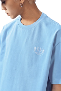 Light blue MEDM SS25 Basic Embroidery Tee designed for a relaxed fit with stylish logo detail