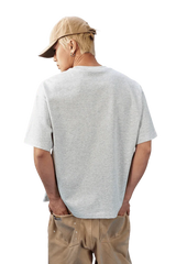 Back view of a man wearing a MEDM SS25 Basic Embroidery Tee in gray, paired with casual beige pants.