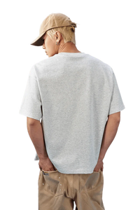Back view of a man wearing a MEDM SS25 Basic Embroidery Tee in gray, paired with casual beige pants.