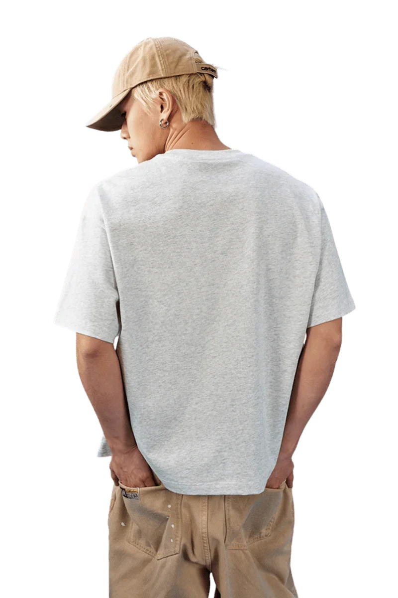 Back view of a man wearing a MEDM SS25 Basic Embroidery Tee in gray, paired with casual beige pants.