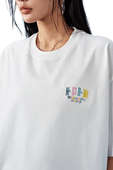 White MEDM SS25 Basic Embroidery Tee featuring colorful logo on the front for casual wear