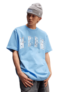 Model wearing the MEDM SS25 Basic Gem Series Tee in light blue with bold graphic design