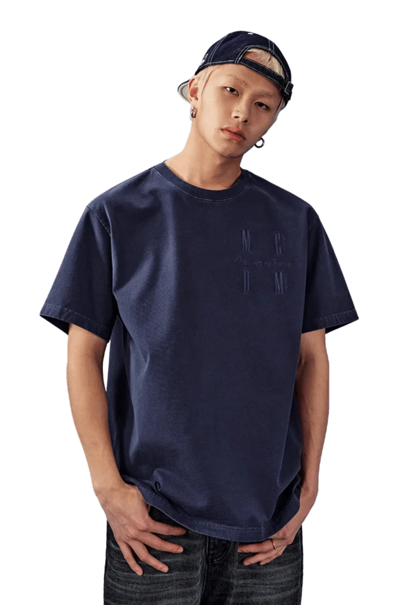 Model wearing the MEDM SS25 Basic Logo Washed Tee in navy blue, styled casually with jeans