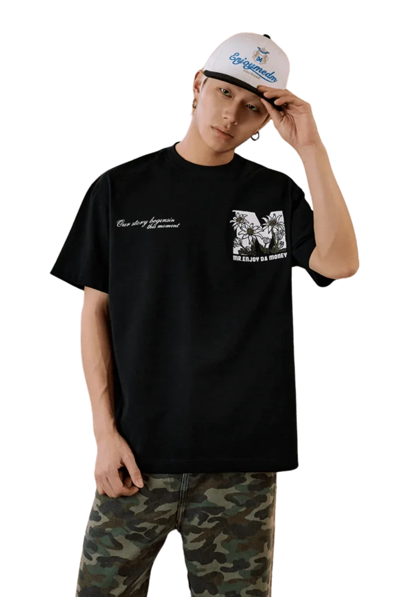 MEDM SS25 Big M Daisy Print Tee in black worn with camo pants and a cap for a stylish streetwear look