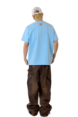 Back view of man's light blue MEDM SS25 Cat Velcro Embroidery Tee paired with casual brown cargo pants