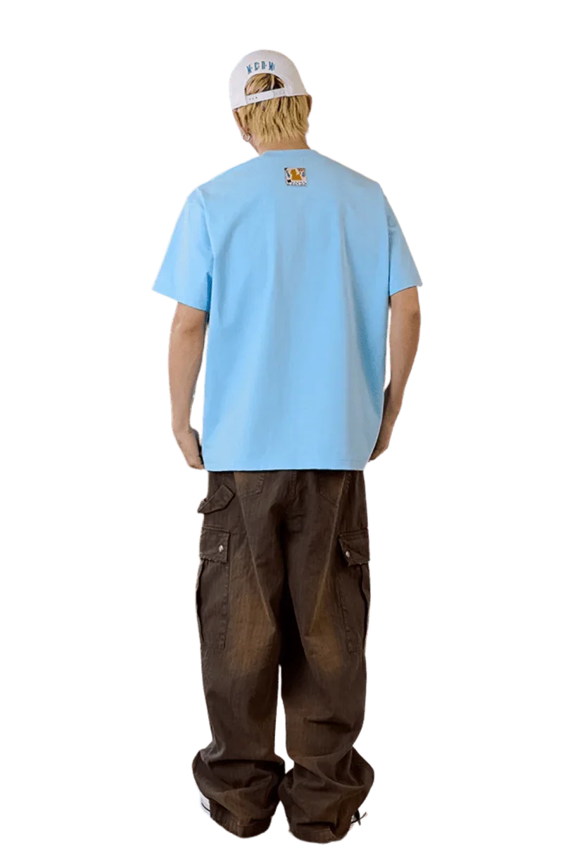 Back view of man's light blue MEDM SS25 Cat Velcro Embroidery Tee paired with casual brown cargo pants