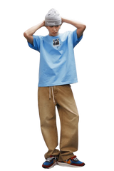 Model wearing a light blue MEDM SS25 Dog Polaroid Tee with beige pants and a beanie
