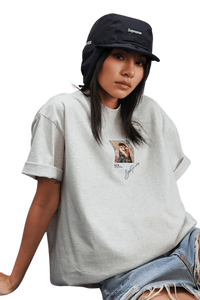 Stylish woman wearing a MEDM SS25 Dog Polaroid Tee in grey, paired with a black Supreme hat