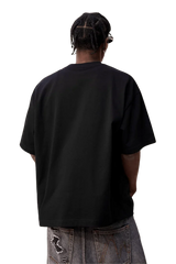 Back view of MEDM SS25 Felt Embossed Basic Tee in black, styled with loose denim pants