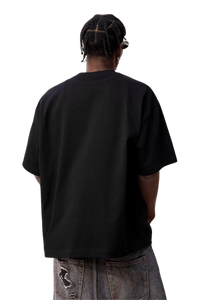 Back view of MEDM SS25 Felt Embossed Basic Tee in black, styled with loose denim pants