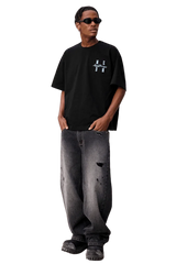 Model wearing MEDM SS25 Felt Embossed Basic Tee in black with stylish distressed jeans