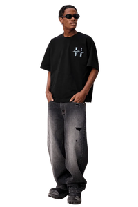 Model wearing MEDM SS25 Felt Embossed Basic Tee in black with stylish distressed jeans