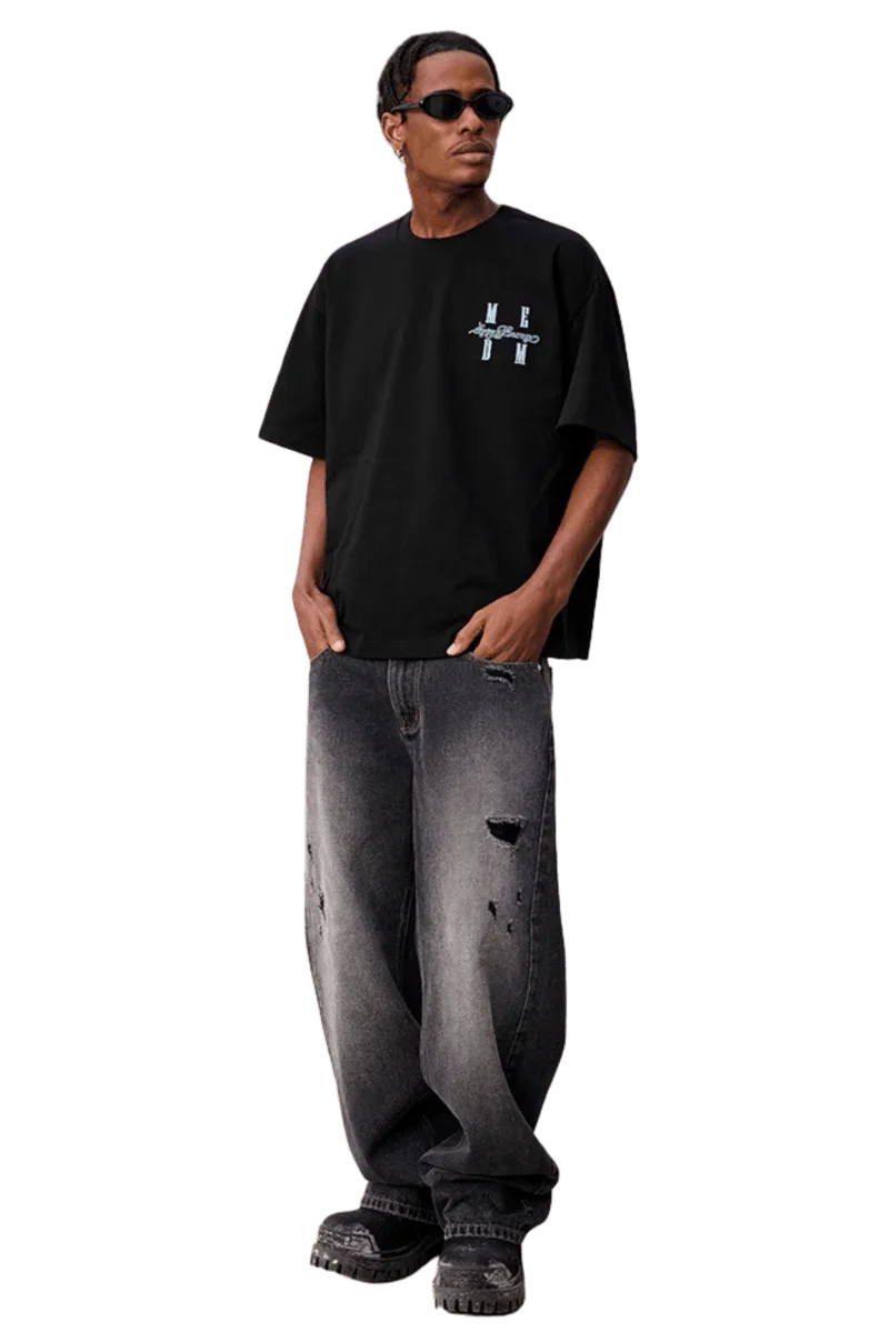 Model wearing MEDM SS25 Felt Embossed Basic Tee in black with stylish distressed jeans