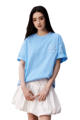 Model wearing a light blue MEDM SS25 Felt Embossed Basic Tee paired with a white skirt