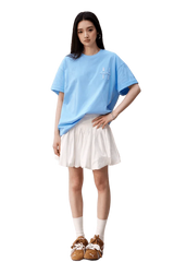Model wearing blue MEDM SS25 Felt Embossed Basic Tee paired with a white skirt and stylish shoes