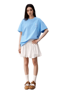 Model wearing blue MEDM SS25 Felt Embossed Basic Tee paired with a white skirt and stylish shoes