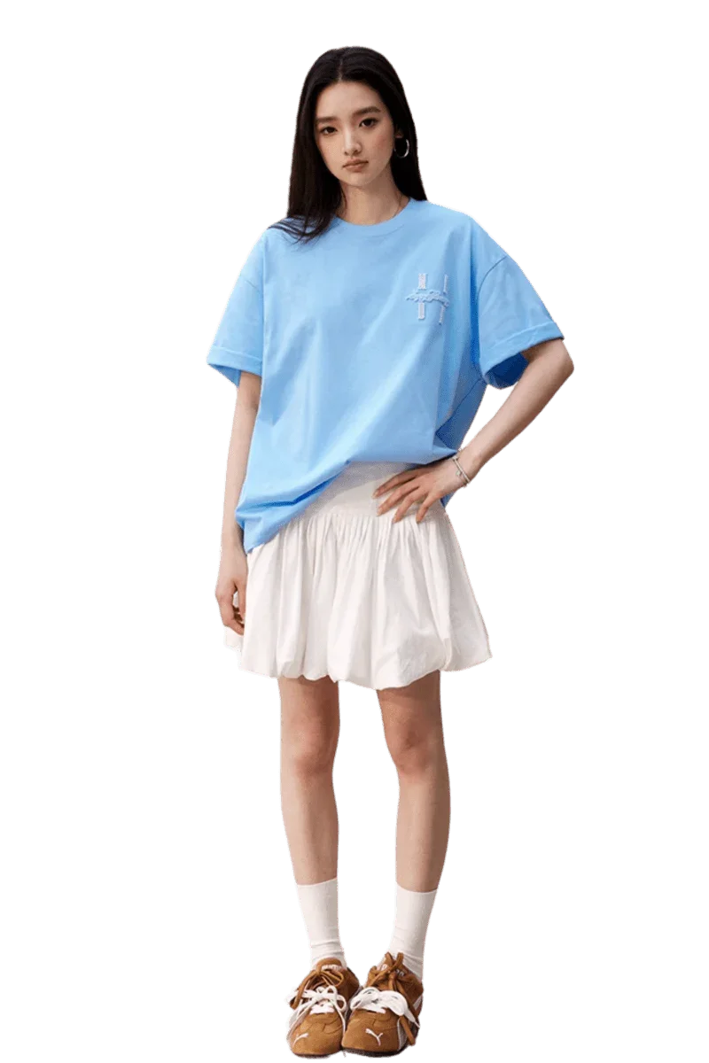 Model wearing blue MEDM SS25 Felt Embossed Basic Tee paired with a white skirt and stylish shoes
