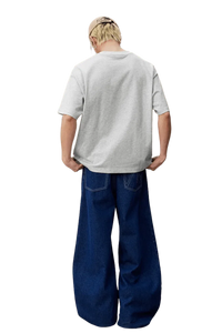 Model wearing MEDM SS25 Felt Embossed Basic Tee in gray from the back with loose-fit jeans