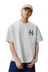 Model wearing the MEDM SS25 Felt Embossed Basic Tee in gray with a relaxed fit and unique design