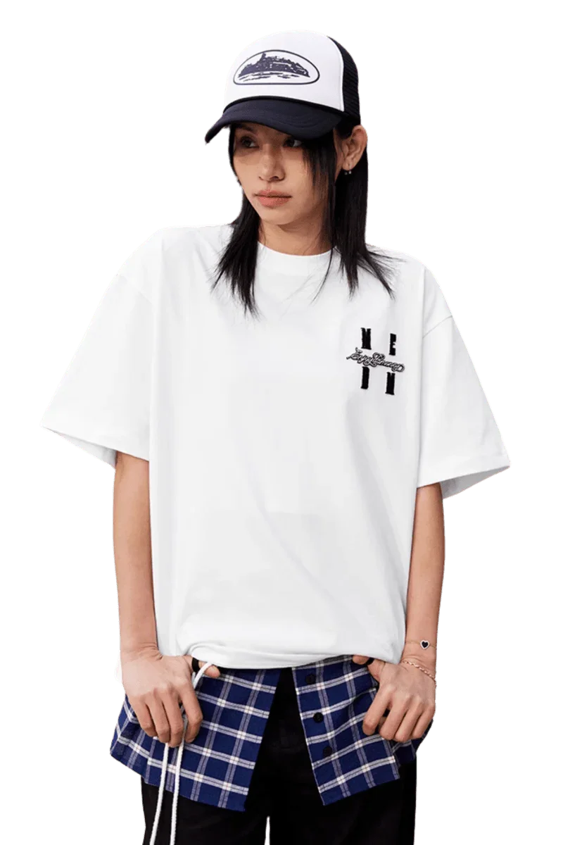 Model wearing a white MEDM SS25 Felt Embossed Basic Tee layered over a plaid shirt