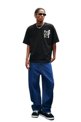 Model wearing MEDM SS25 Floral Embroidery Tee in black with jeans and sneakers, showcasing casual streetwear style.