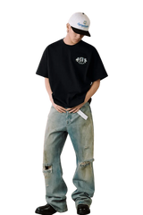 Model wearing MEDM SS25 Floral Felt Embossed Tee with distressed jeans and a cap
