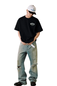 Model wearing MEDM SS25 Floral Felt Embossed Tee with distressed jeans and a cap