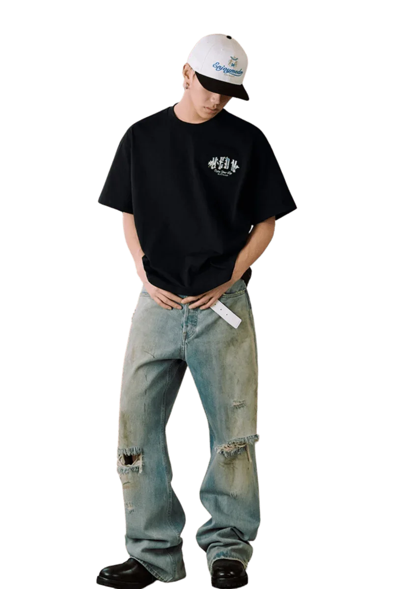 Model wearing MEDM SS25 Floral Felt Embossed Tee with distressed jeans and a cap