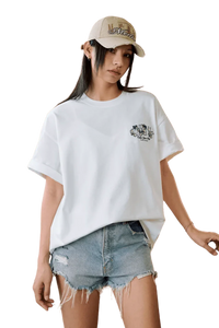 Model wearing MEDM SS25 Floral Felt Embossed Tee with denim shorts and a stylish cap