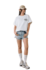 Model wearing MEDM SS25 Floral Felt Embossed Tee with denim shorts and a cap for a casual look