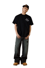 Model wearing MEDM SS25 Four Color Velvet Embossed Tee with relaxed fit and black distressed jeans