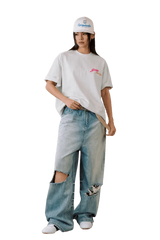 Model wearing a MEDM SS25 Four Color Velvet Embossed Tee paired with distressed jeans and a cap