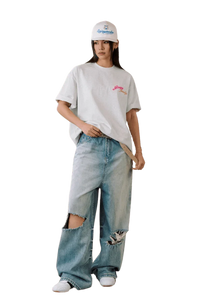 Model wearing a MEDM SS25 Four Color Velvet Embossed Tee paired with distressed jeans and a cap