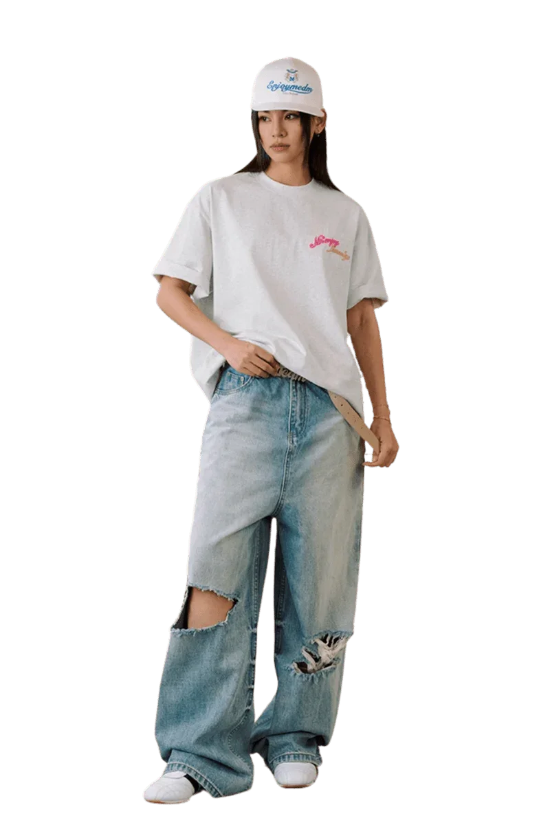 Model wearing a MEDM SS25 Four Color Velvet Embossed Tee paired with distressed jeans and a cap