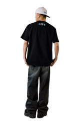 Male model wearing MEDM SS25 Macaron Velvet Embossed Tee in black, styled with baggy jeans