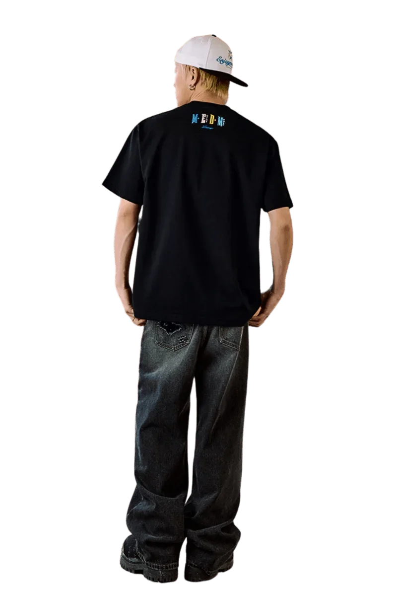 Male model wearing MEDM SS25 Macaron Velvet Embossed Tee in black, styled with baggy jeans