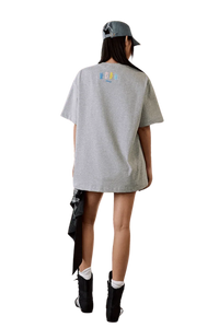 Model wearing MEDM SS25 Macaron Velvet Embossed Tee in gray from the back, styled with a denim cap