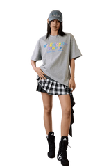 Model wearing MEDM SS25 Macaron Velvet Embossed Tee with a plaid skirt and accessories