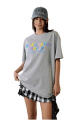 MEDM SS25 Macaron Velvet Embossed Tee in gray, styled casually with a plaid skirt and cap